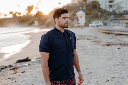 Man on a beach wearing a Floatee anti-drowning T-shirt for adults, color blue with short sleeves