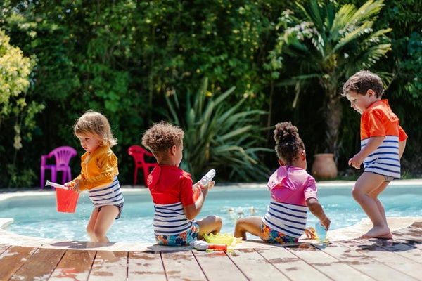Children with anti-drowning tee-shirt playing next to a pool