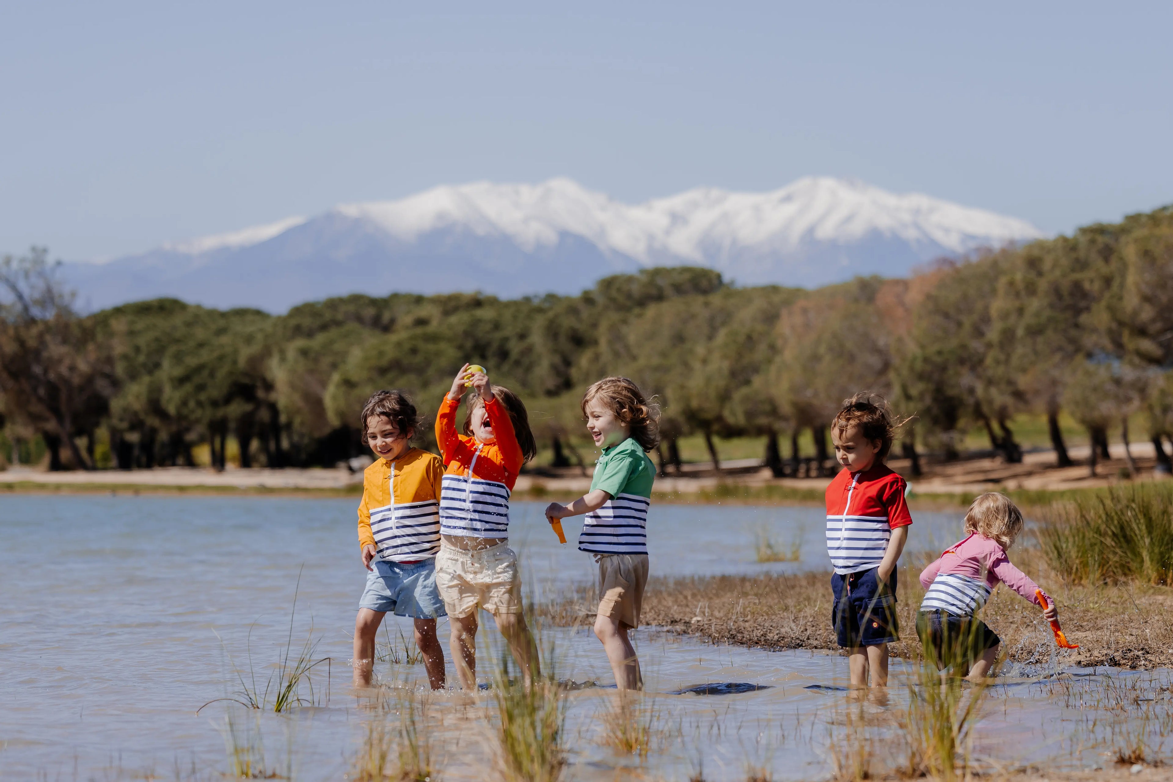 Children with the anti-drowning tee-shirt playing next to a lake