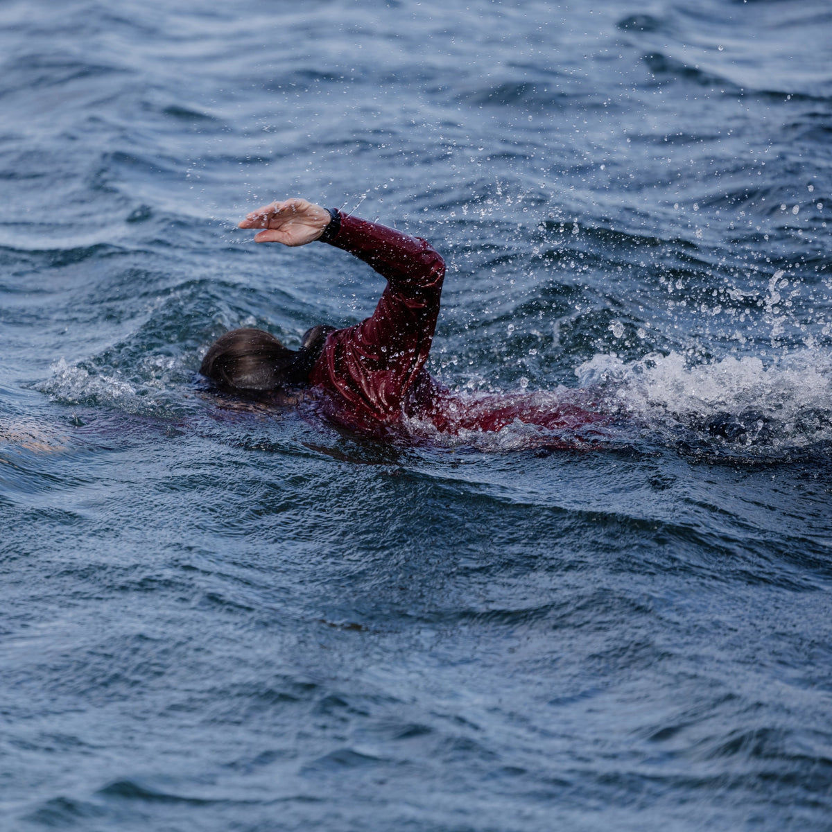 Woman swimming in the sea and wearing a Floatee anti-drowning T-shirt for adults, color red with short sleeves