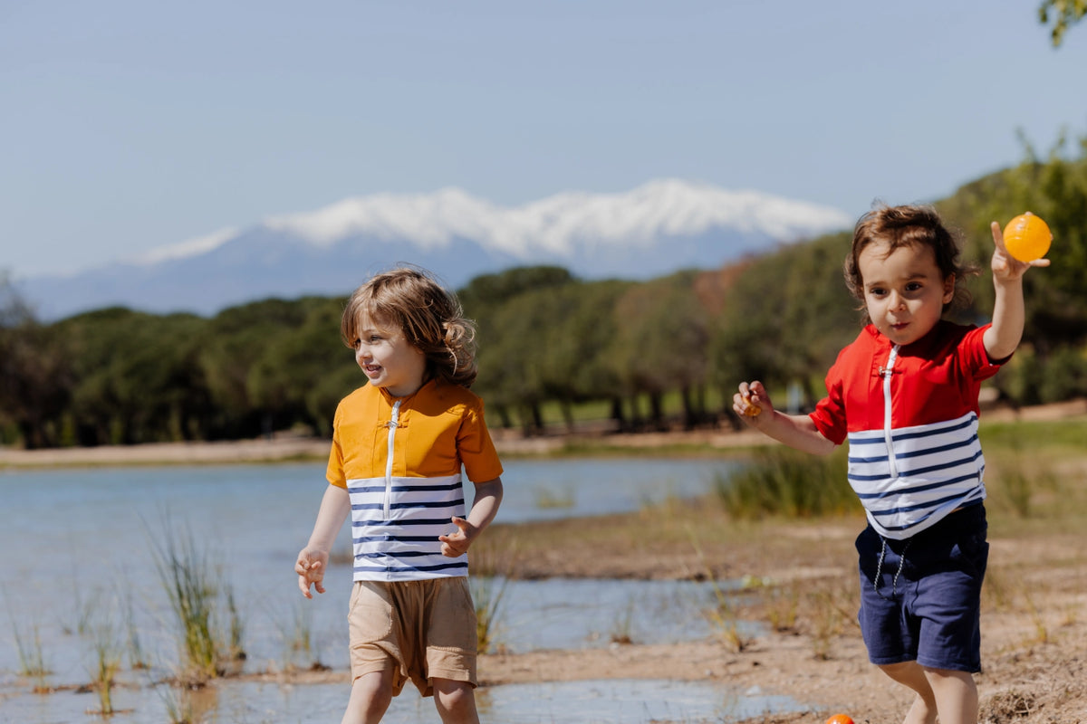 Two children wearing Floatee anti-drowning T-shirts near a lake
