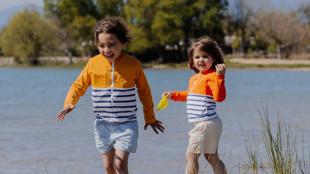 Two children wearing Floatee anti-drowning T-shirts near a lake