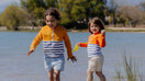 Two children wearing Floatee anti-drowning T-shirts near a lake
