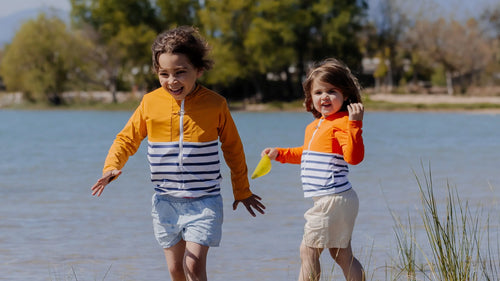 Two children wearing Floatee anti-drowning T-shirts near a lake